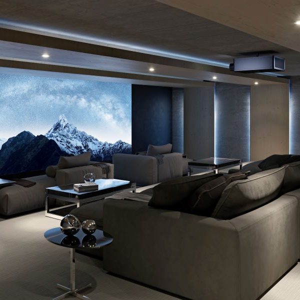 A home theater with chaise lounges, a large screen depicting snow-capped mountains, and a Sony projector.